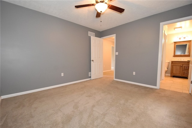 unfurnished bedroom featuring light colored carpet, ensuite bath, and ceiling fan