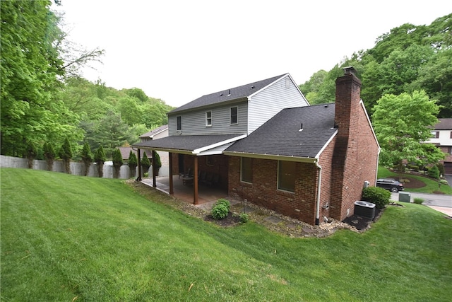 rear view of property with central AC, a patio area, and a lawn