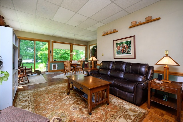 living room featuring plenty of natural light, a paneled ceiling, and parquet flooring