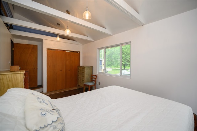 bedroom featuring lofted ceiling with beams and a closet