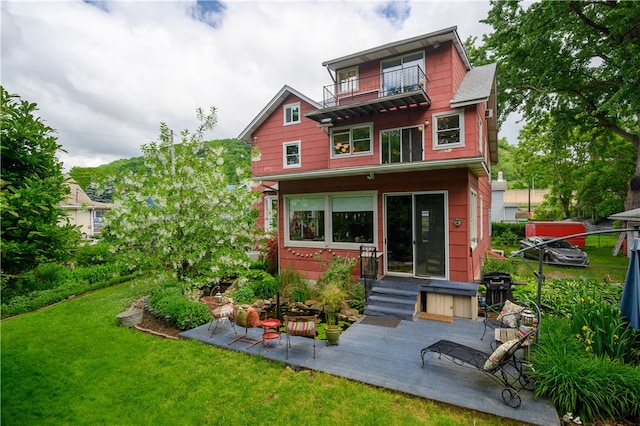 view of front of house featuring a front lawn, a balcony, and a patio