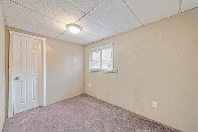 empty room featuring carpet flooring and a paneled ceiling