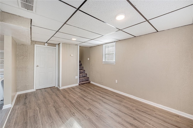 basement featuring a paneled ceiling and hardwood / wood-style floors