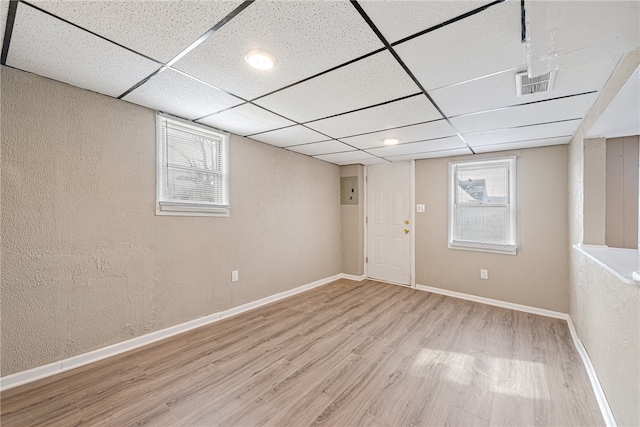 basement with a healthy amount of sunlight, light wood-type flooring, and a drop ceiling