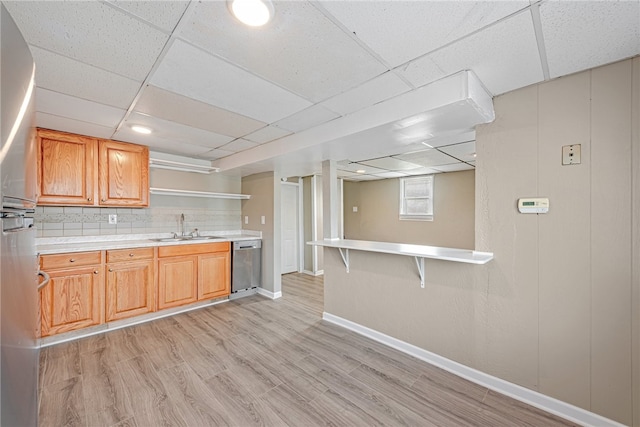 kitchen featuring a kitchen breakfast bar, dishwasher, light wood-type flooring, a paneled ceiling, and sink