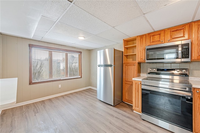 kitchen with stainless steel appliances, light wood-type flooring, and a drop ceiling