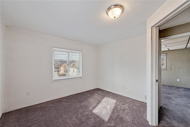 unfurnished room featuring dark colored carpet