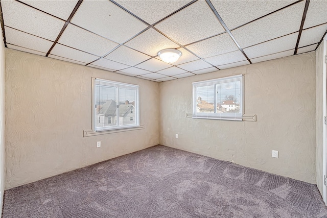 carpeted empty room with a paneled ceiling and plenty of natural light