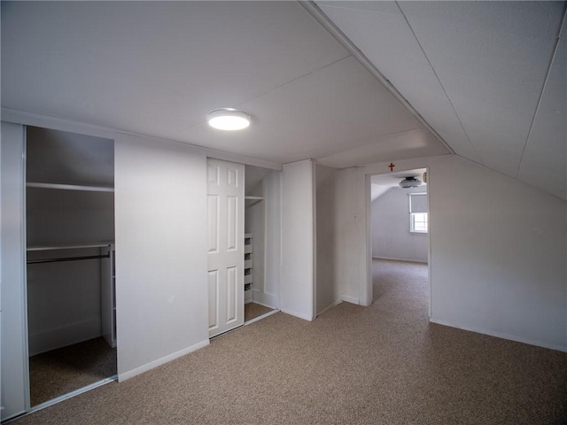 additional living space featuring vaulted ceiling and carpet flooring