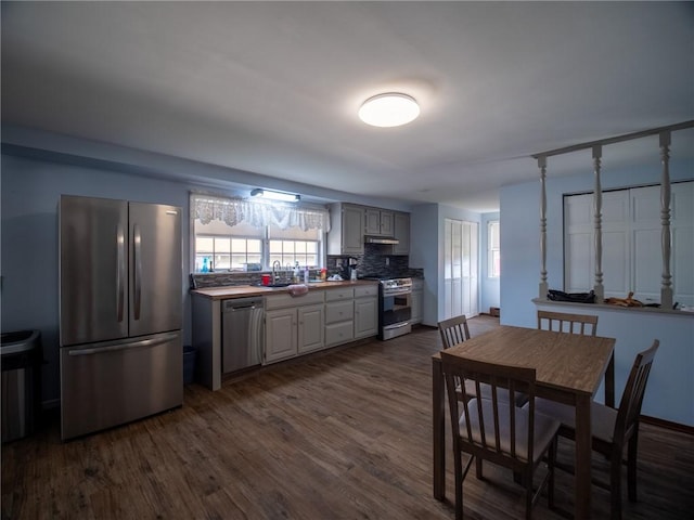 kitchen featuring dark hardwood / wood-style flooring, decorative backsplash, gray cabinets, and appliances with stainless steel finishes