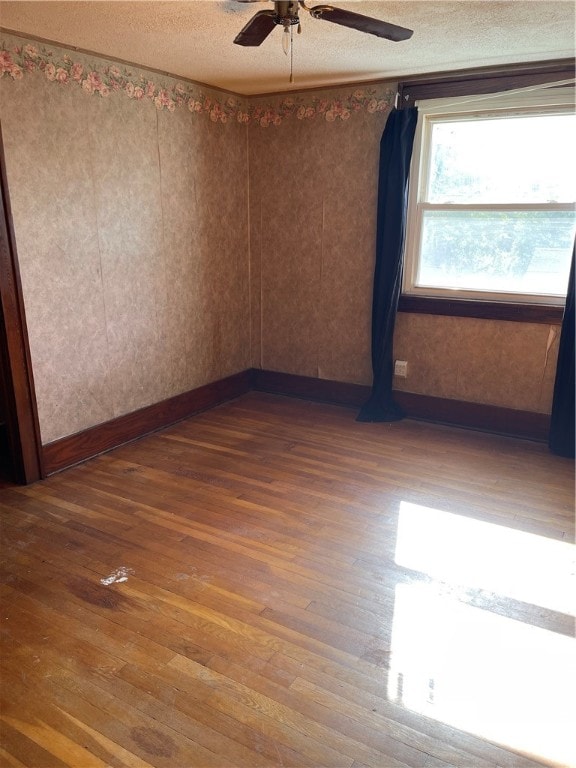 unfurnished room featuring ceiling fan, hardwood / wood-style flooring, and a textured ceiling