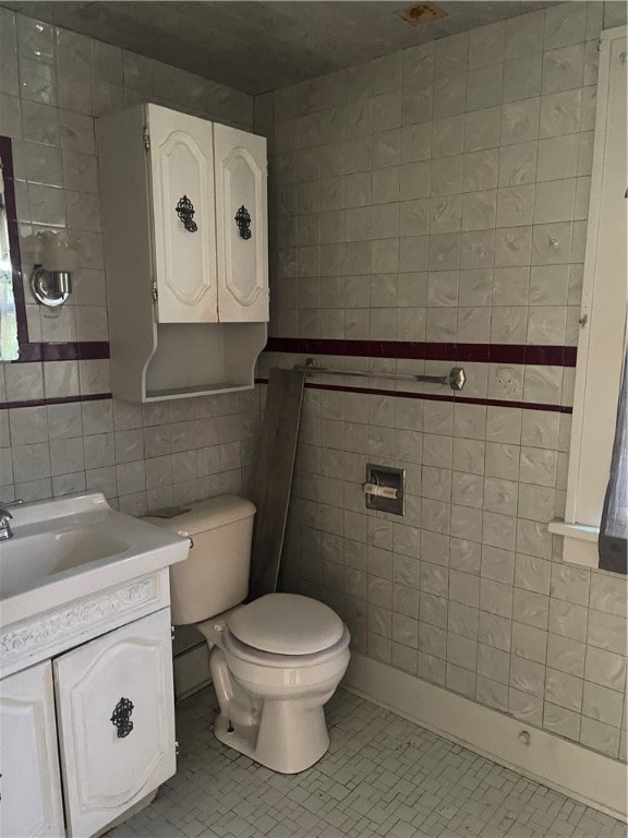 bathroom with tile patterned flooring, tile walls, toilet, and vanity