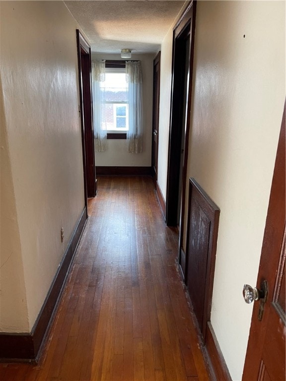 hall with dark hardwood / wood-style flooring and a textured ceiling