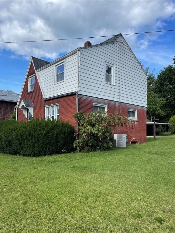 view of side of property featuring central AC and a yard