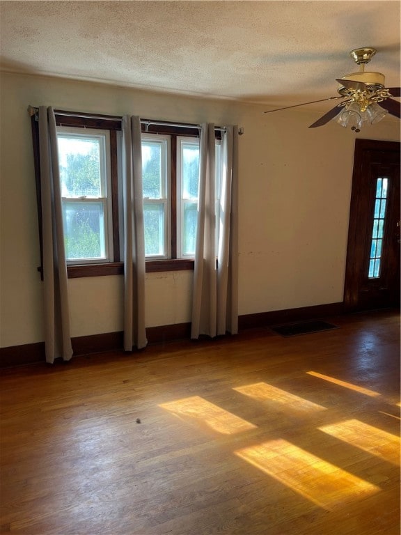 empty room with a textured ceiling, ceiling fan, and hardwood / wood-style flooring