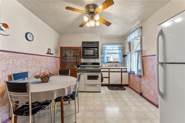 kitchen with white fridge, double oven range, ceiling fan, light tile flooring, and black microwave