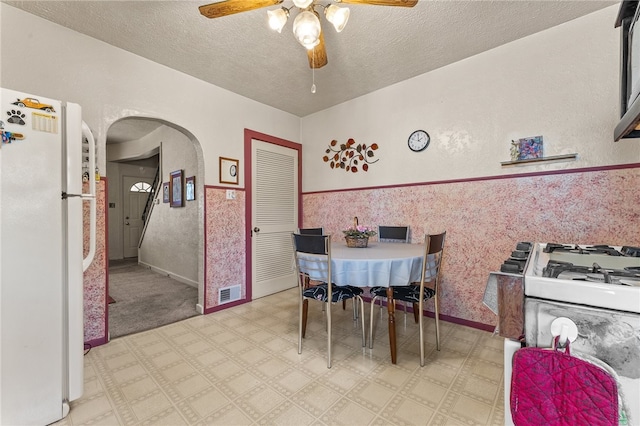 dining space with a textured ceiling, ceiling fan, and carpet