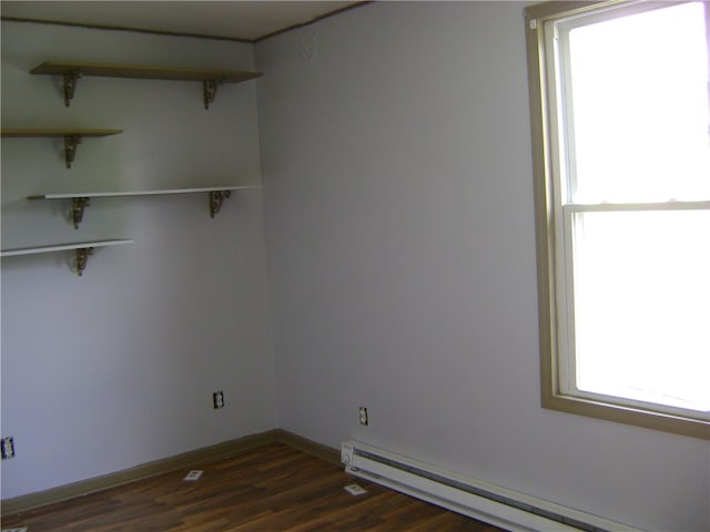 unfurnished room with dark hardwood / wood-style flooring and a baseboard heating unit