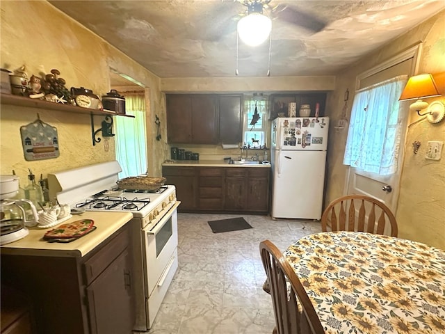 kitchen featuring sink, white appliances, ceiling fan, dark brown cabinetry, and light tile floors