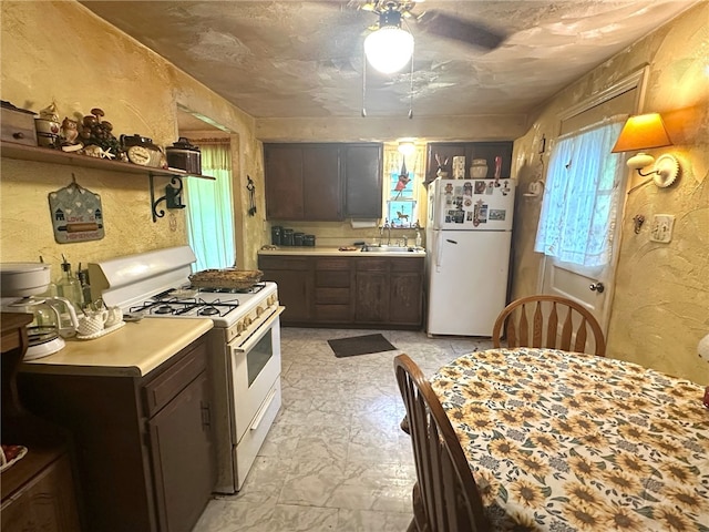 kitchen with white appliances, dark brown cabinetry, sink, light tile floors, and ceiling fan