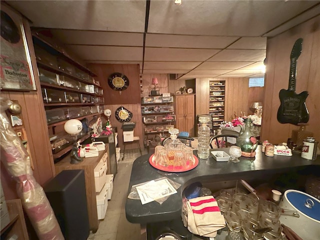 dining area with a drop ceiling and wood walls