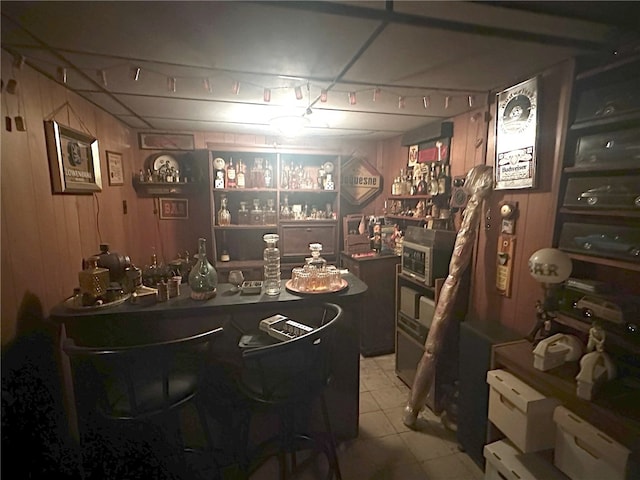 bar with wood walls and light tile flooring