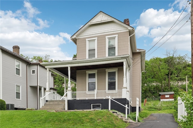 front of property with covered porch, a front lawn, and central AC unit