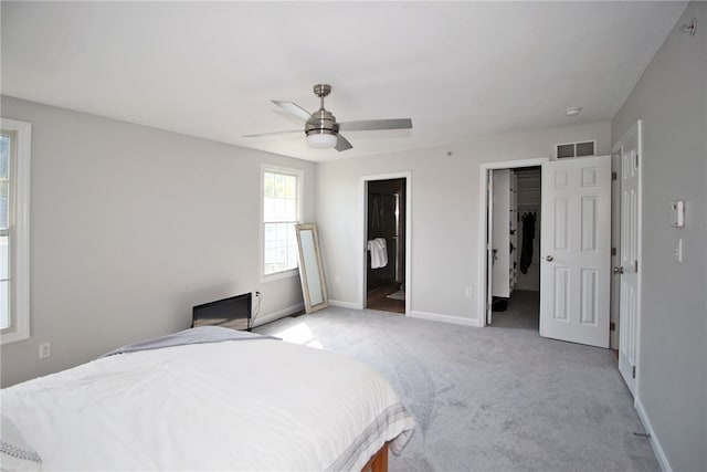 bedroom featuring ceiling fan, a closet, a spacious closet, ensuite bathroom, and light colored carpet