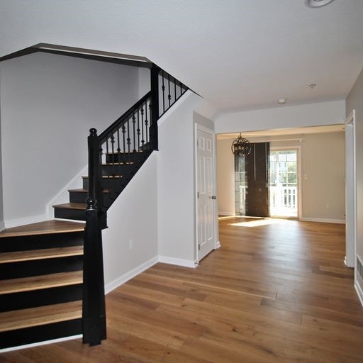 stairs featuring an inviting chandelier and wood-type flooring