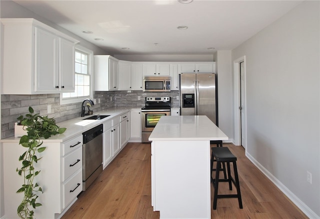 kitchen featuring stainless steel appliances, sink, light hardwood / wood-style floors, and a kitchen island