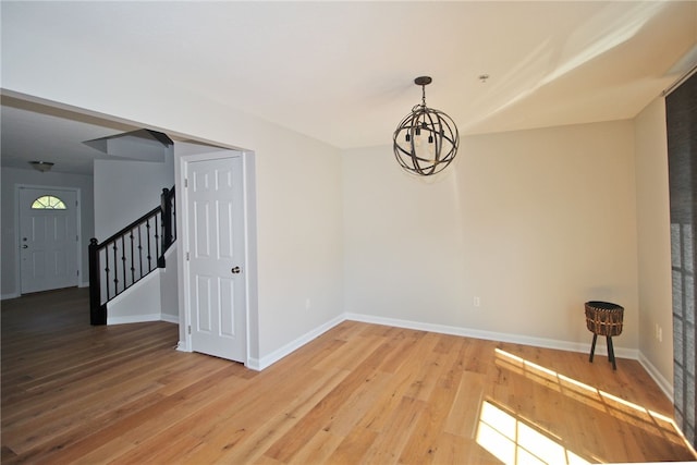 unfurnished room with a chandelier and wood-type flooring