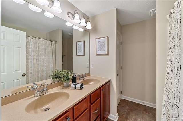 bathroom featuring tile flooring, oversized vanity, double sink, and a textured ceiling