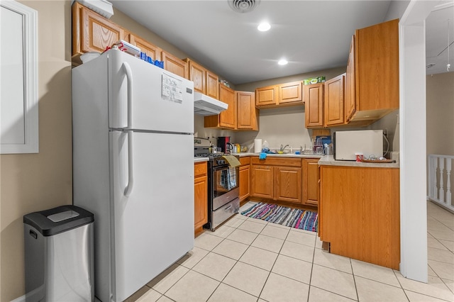 kitchen with sink, light tile flooring, stainless steel range with gas stovetop, and white fridge