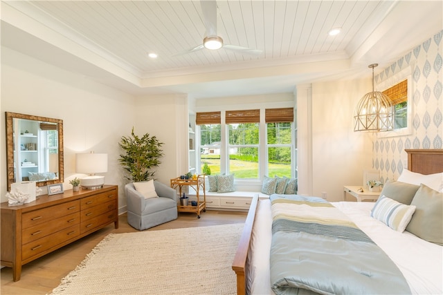 bedroom featuring a chandelier, light hardwood / wood-style flooring, and a tray ceiling