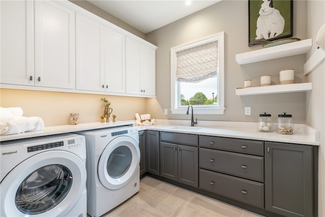 clothes washing area featuring sink, independent washer and dryer, light tile floors, and cabinets