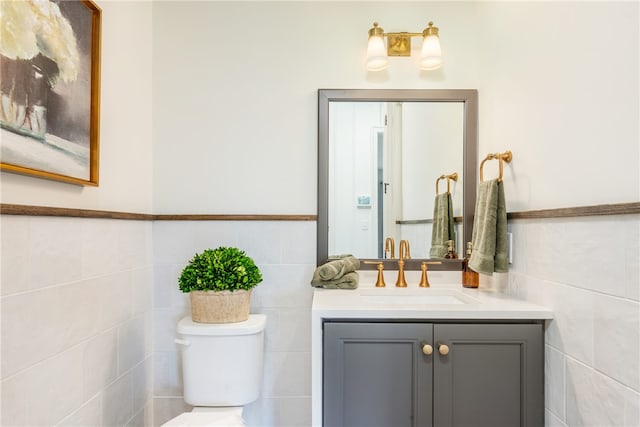 bathroom with vanity, toilet, and tile walls