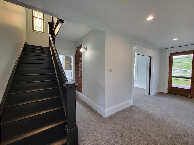 stairs featuring carpet flooring and brick wall