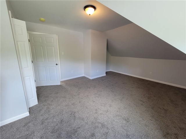 bonus room with dark colored carpet and lofted ceiling