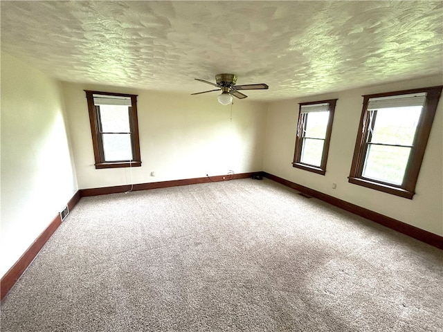 carpeted empty room featuring ceiling fan and a textured ceiling