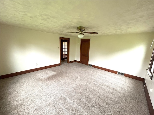 carpeted spare room featuring ceiling fan and a textured ceiling