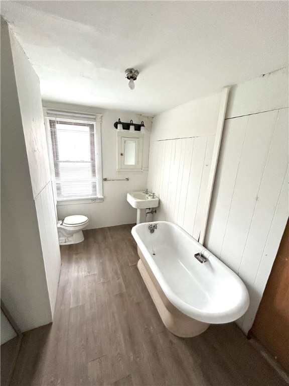 bathroom featuring a bathing tub, toilet, and wood-type flooring