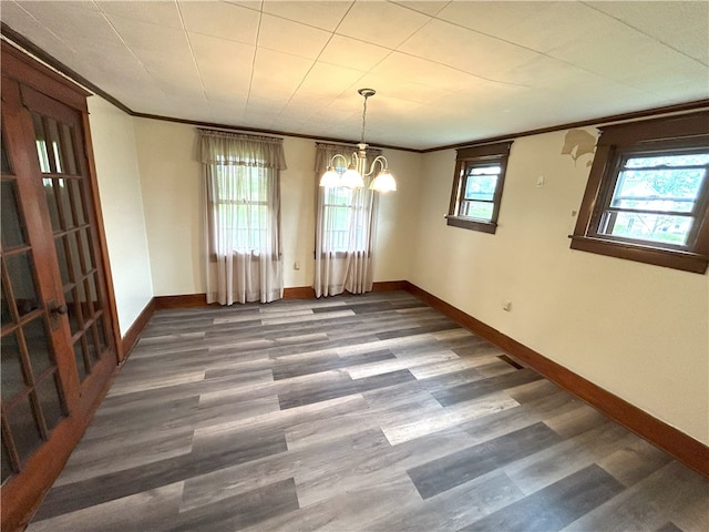 spare room featuring ornamental molding, an inviting chandelier, and dark wood-type flooring