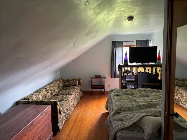 bedroom featuring a textured ceiling, vaulted ceiling, and hardwood / wood-style floors