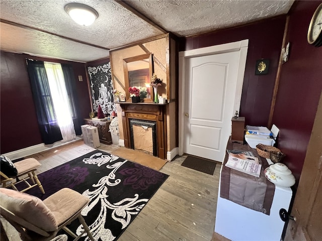 interior space with a textured ceiling, a large fireplace, and light hardwood / wood-style flooring