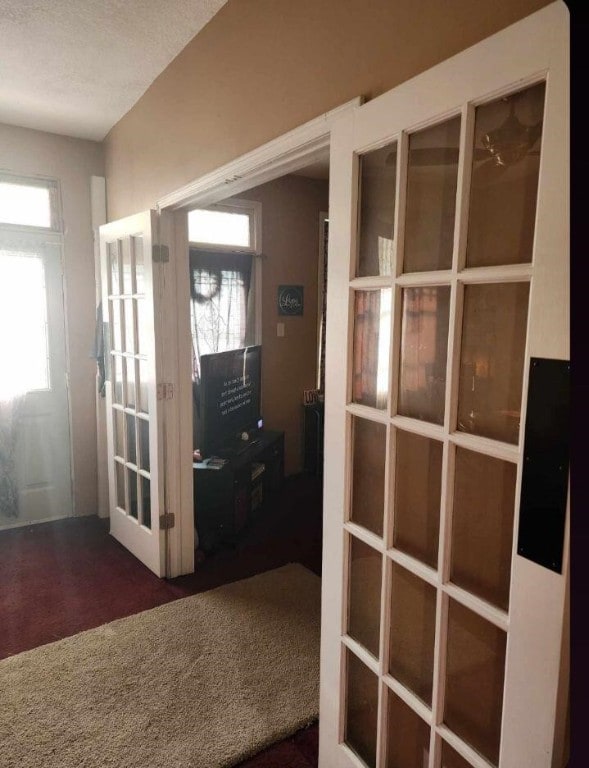 entrance foyer with plenty of natural light, dark colored carpet, and french doors