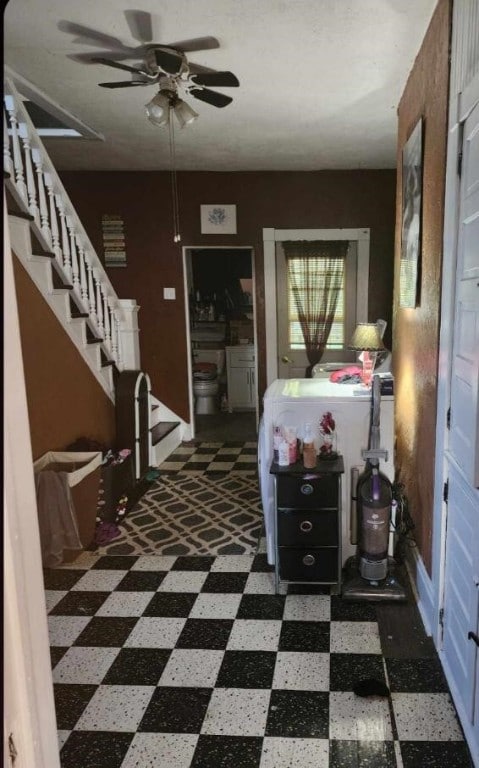 foyer featuring ceiling fan and dark tile floors