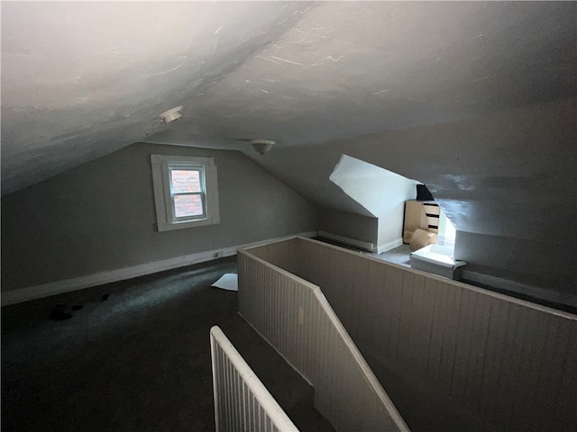 additional living space featuring lofted ceiling and dark carpet