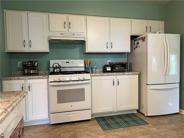 kitchen with white appliances, white cabinets, light tile patterned floors, and light stone countertops