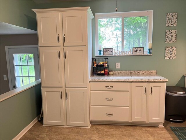 kitchen with light tile patterned flooring, white cabinetry, and a healthy amount of sunlight