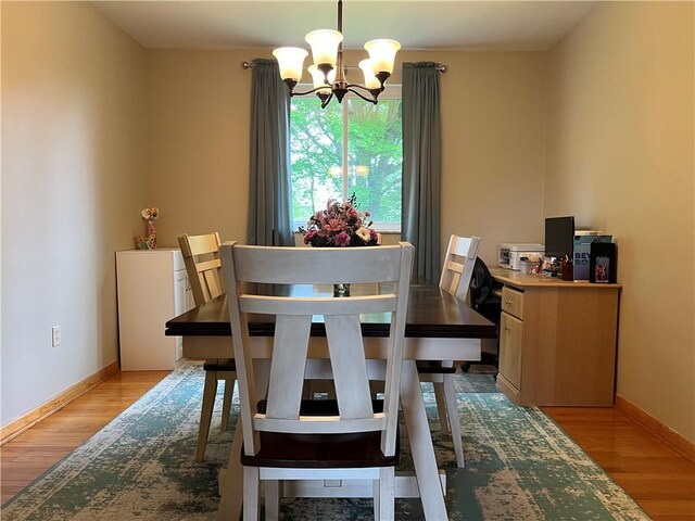 dining area with light hardwood / wood-style floors and a notable chandelier